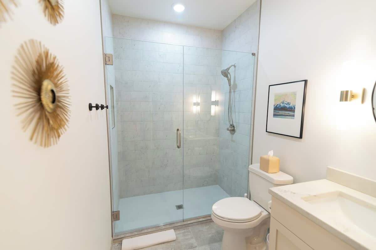 A modern bathroom with a glass-enclosed shower, a toilet, and a sink.