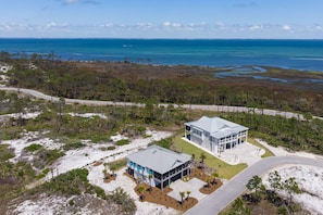 An aerial view of a coastal property with two modern buildings, a road, and a beach.