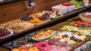 A buffet with various food items including fruits, cheeses, and meats.