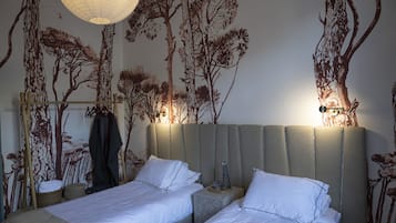 Quarto de hotel com duas camas, um mural grande na parede e um lustre.