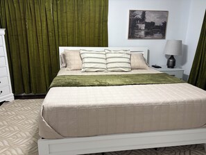 A neatly made bed with a quilted cover, a bedside lamp, and a nightstand with a remote control.