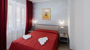 A hotel room with a bed, a nightstand, a wall-mounted light, and a painting. - AFFITTACAMERE ALESSIA (Sanremo)