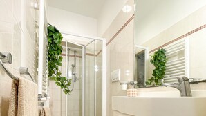 A bathroom with a glass shower enclosure, a toilet, a sink, and a mirror. - Americana beach house (Rimini)
