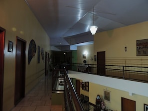 Um interior com vários níveis, com escada, corrimãos e diversos detalhes decorativos nas paredes.