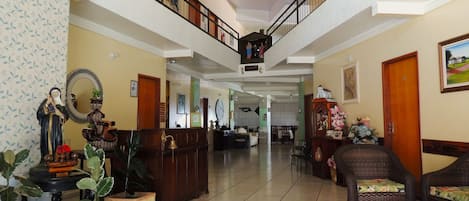 Eine geräumige Lobby mit hoher Decke, einer Treppe und einer Rezeption.