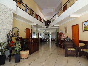 A spacious lobby with a high ceiling, a staircase, and a reception desk. - Pousada Santa Rita (Abadiania)