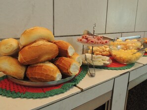 A buffet table with various food items including bread rolls, ham, and cheese.