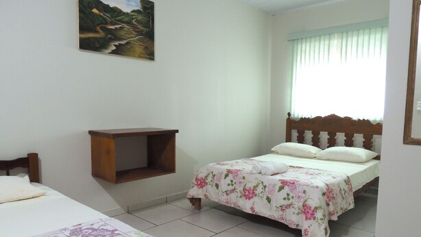 A bedroom with two beds, a wooden headboard, a small wooden shelf, and a painting on the wall.