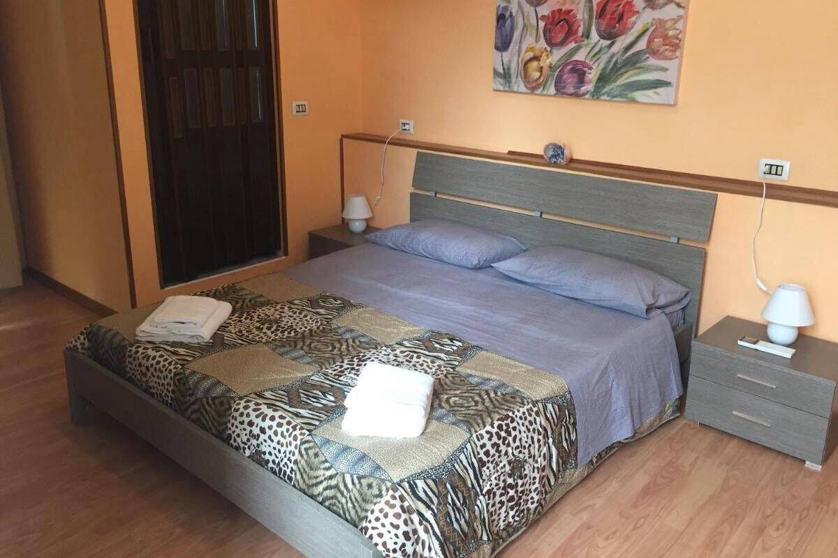 A bedroom with a bed, nightstands, a painting, and a door.