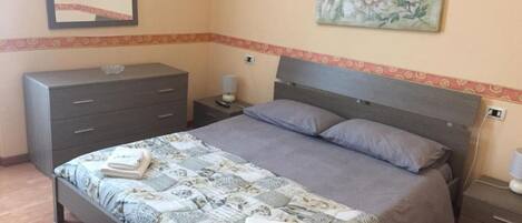A bedroom with a bed, a dresser, a nightstand, and a painting on the wall.