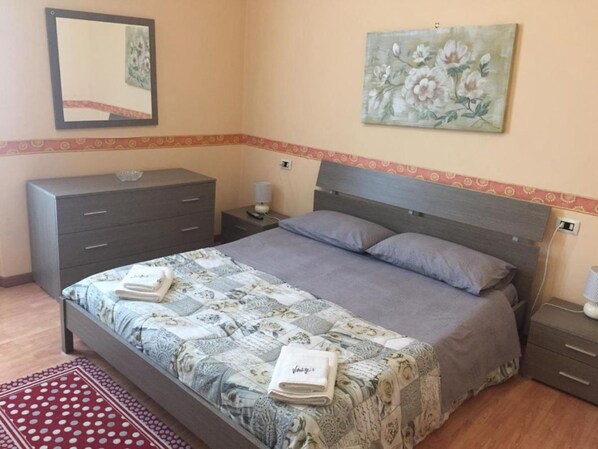 Un dormitorio con cama, cómoda, mesita de noche y un cuadro en la pared.