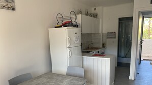 Eine kompakte Küche mit Kühlschrank, Spüle und einer kleinen Essecke mit Tisch und Stühlen.