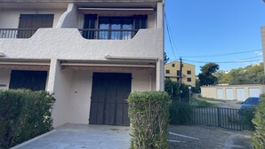 Ein zweistöckiges Gebäude mit Balkon, geschlossenem Eingangstor und gepflasterter Auffahrt.
