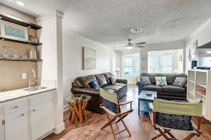 A compact living space with a kitchenette, two leather sofas, a small coffee table, and a ceiling fan. - This stylish condo is located on the second floor of Mustang Island Beach Club. (Port Aransas)