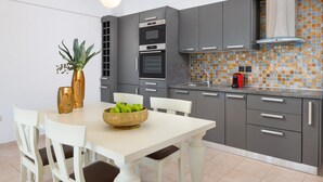 Una cocina moderna con gabinetes grises, salpicadero de azulejos y una mesa de comedor blanca con sillas.