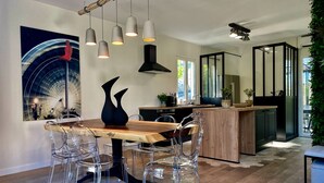 A modern kitchen with a wooden island, clear chairs, and pendant lights.