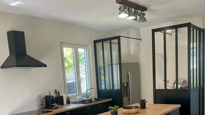 A modern kitchen with a wooden island, black cabinetry, and a stainless steel range hood.