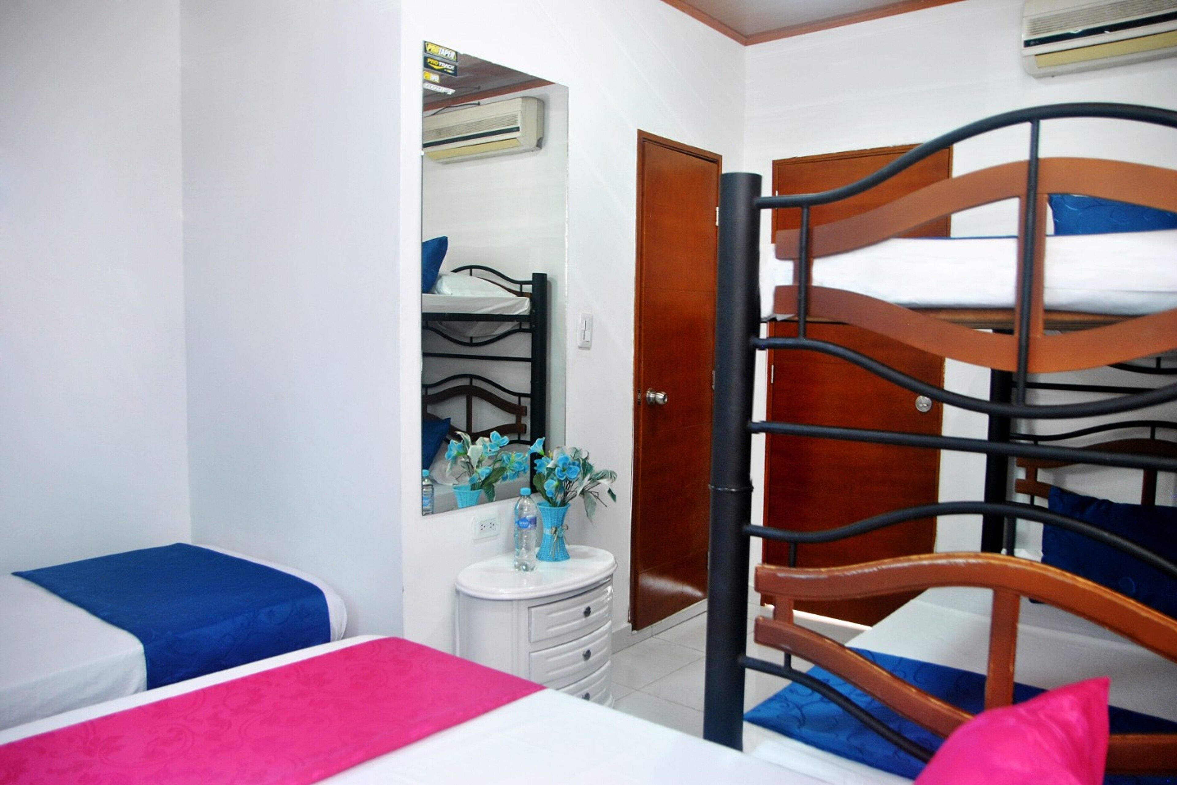 Un dormitorio con literas, una mesita de noche pequeña, un espejo y un aire acondicionado instalado en la pared.