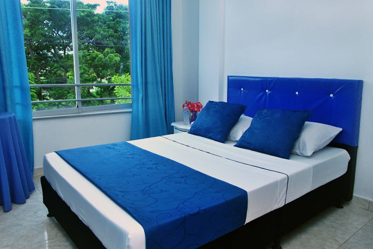 A bed with a blue headboard, white bedding, and a blue bedspread.