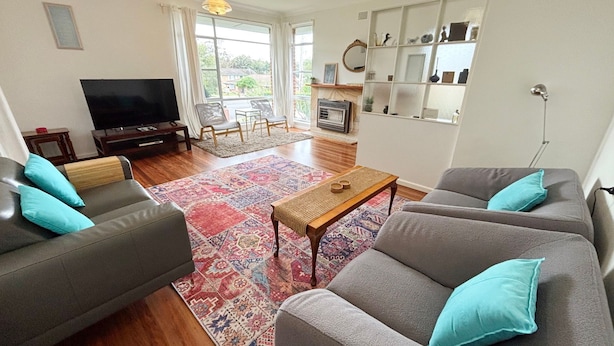 A living room with two sofas, a TV, a fireplace, and a large window.