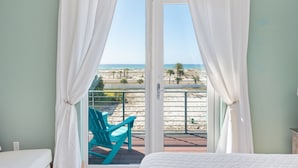 Una habitación con cama, un balcón que ofrece vistas a la playa y una silla.