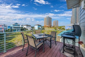 A balcony with a table and chairs, a grill, and a view of high-rise buildings. - Gulf Views, Elevator & Fire Pit (Pensacola Beach)