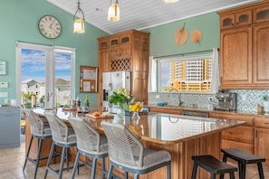 A modern kitchen with a large island, wooden cabinets, and a view of the outside.