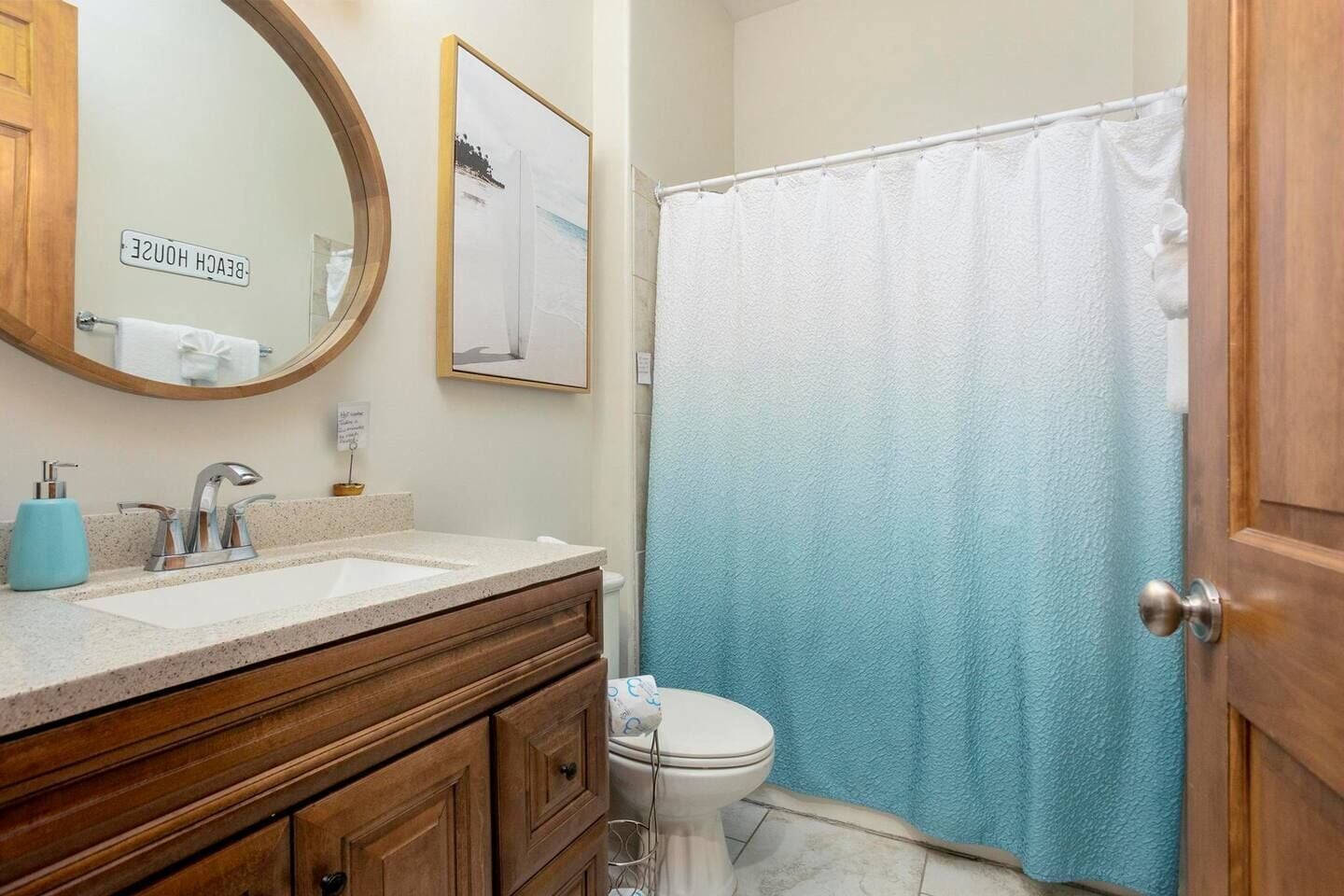 Une salle de bain avec un meuble-lavabo en bois, un évier, un miroir, des toilettes et un rideau de douche.
