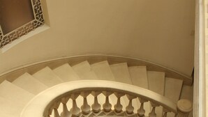 A curved staircase with a balustrade and a handrail. - Grand Domo Hotel (León)