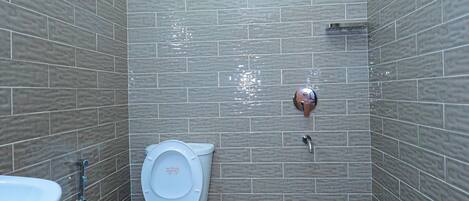 Een compacte badkamer met toilet, wastafel en douche.