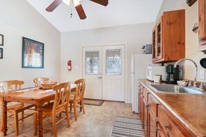 Une cuisine dotée de meubles en bois, d’un évier en acier inoxydable et d’un coin repas avec une table et des chaises en bois.