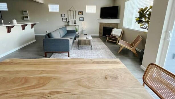 A modern living room with a sofa, coffee table, and a TV mounted above a fireplace.