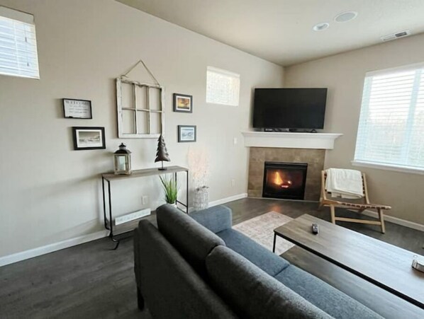A living room with a fireplace, a sofa, a coffee table, and a TV mounted above the fireplace.