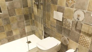Een badkamer met douche, toilet en wastafel.