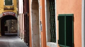 Een smalle straat met gebouwen aan beide kanten, waarvan er één een bordje heeft met de tekst 'RISTORANTE'.