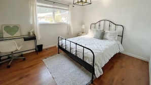 A bedroom with a bed, desk, and window.