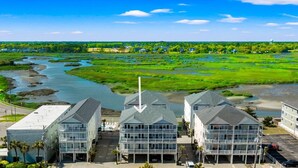 Un hôtel situé sur la côte, composé de plusieurs bâtiments, avec une rivière en arrière-plan et un ciel dégagé.