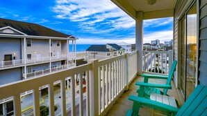 A balcony with a view of the beach and cityscape.