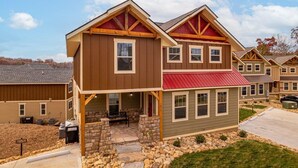 A two-story residential building with a stone foundation, a covered patio, and a red roof. - Time for Us (Gatlinburg)