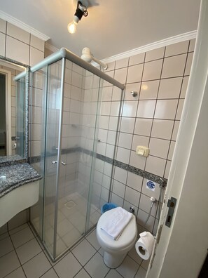 Un baño moderno con cabina de ducha de vidrio, inodoro y lavamanos con encimera de granito.