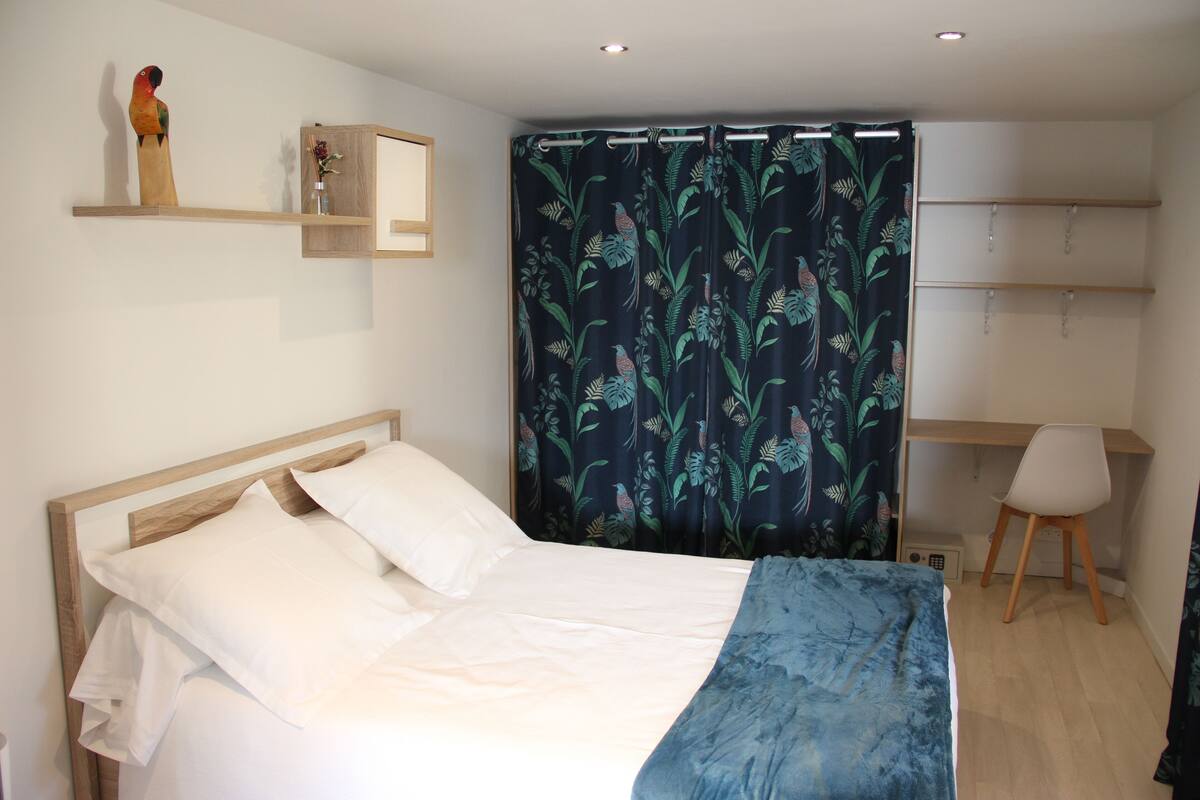 A bedroom with a bed, a desk, and a chair.