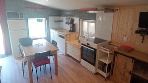 A compact kitchen with a dining area, a microwave, a refrigerator, a stove, and a sink. - A la fontaine fleurie (Fremifontaine)