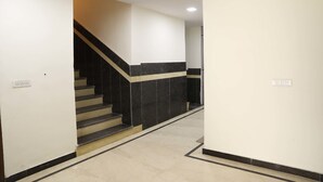 A hallway with a staircase leading to another floor, white walls, and a tiled floor. - OYO Rooms 486 IGI Airport Near Main Road (New Delhi)