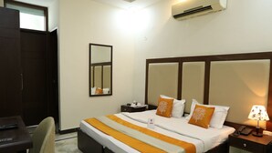A hotel room with a large bed, a desk, a chair, a nightstand, and an air conditioning unit. - OYO Rooms 486 IGI Airport Near Main Road (New Delhi)