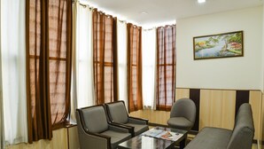 A room with a sofa, two armchairs, a coffee table, and a painting on the wall. - OYO Rooms 486 IGI Airport Near Main Road (New Delhi)