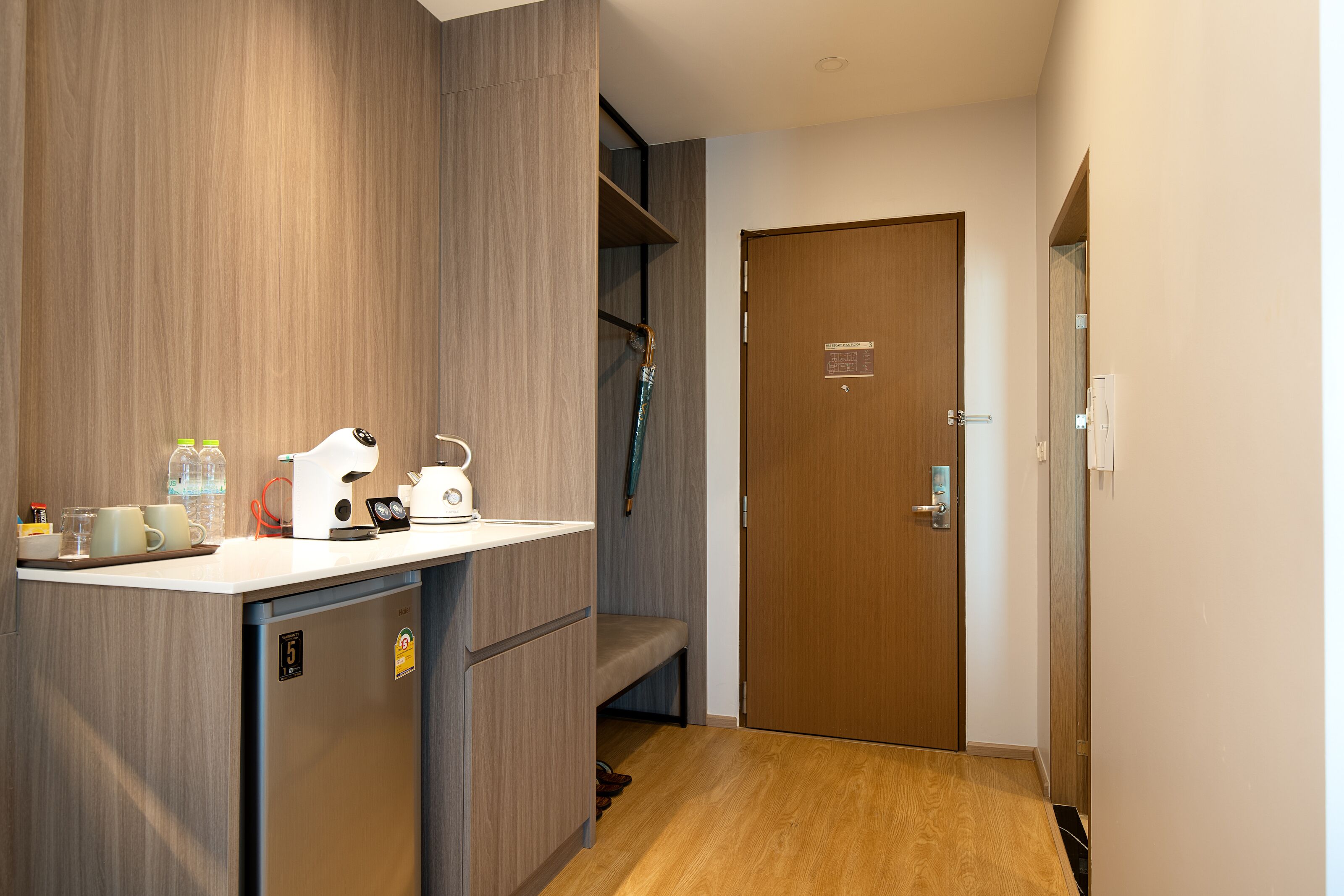 A compact kitchenette with a coffee machine, a kettle, and a small refrigerator.