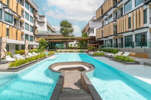 Una piscina al aire libre, sombrillas, sillones reclinables de piscina