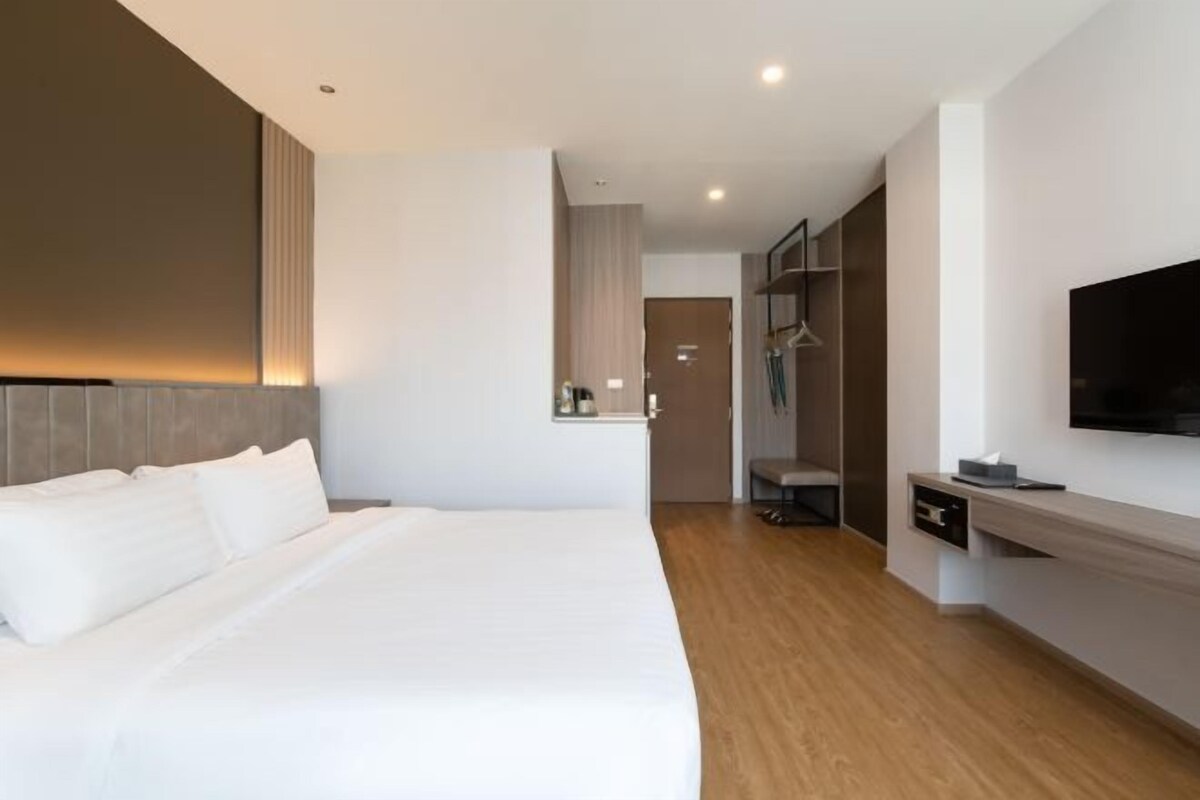 Ein modernes Hotelzimmer mit einem großen Bett, einem flachbildfernseher an der Wand und Holzboden.