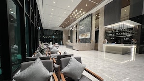 Un vestíbulo moderno con asientos, un mostrador de recepción y una zona de bar.