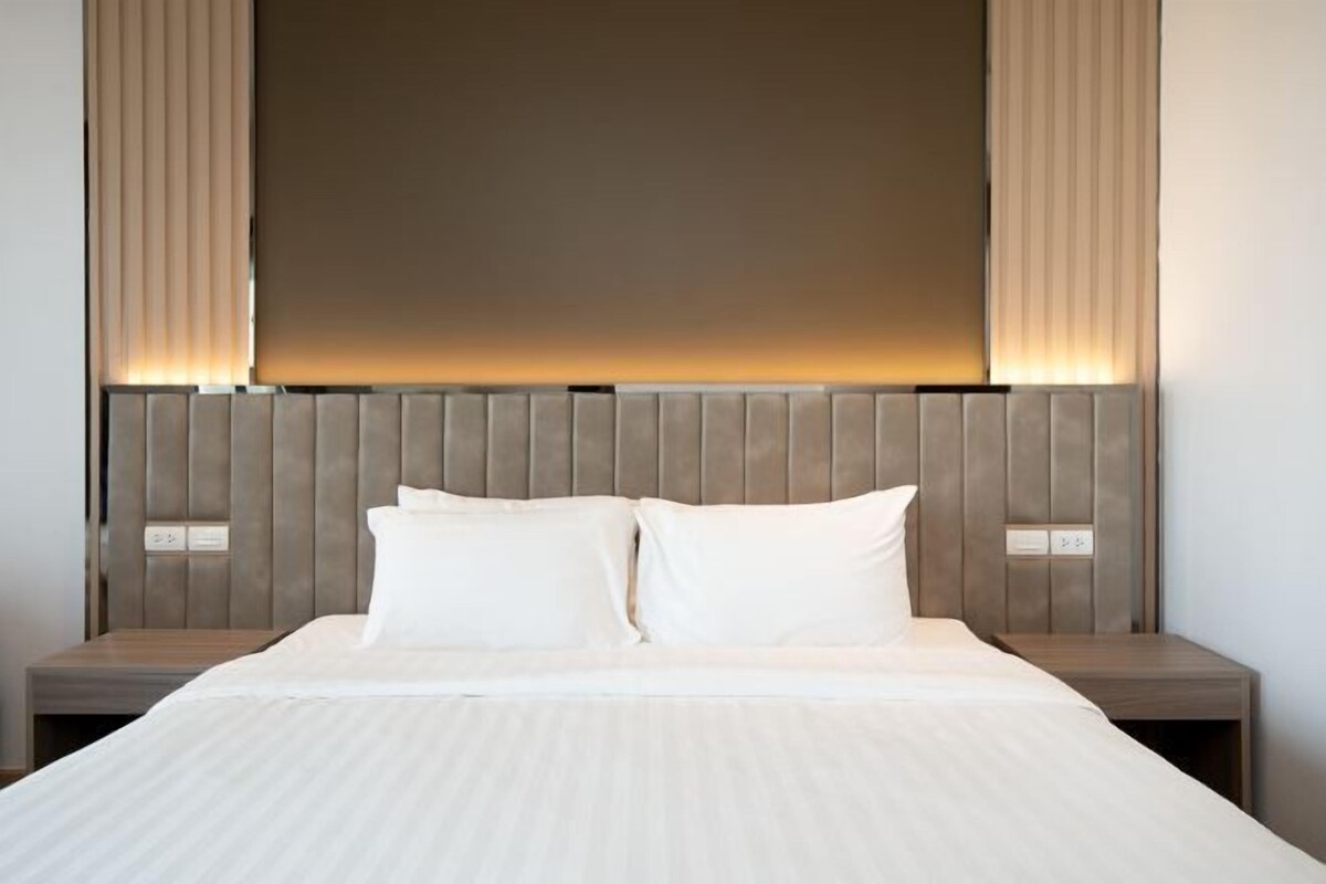 Habitación de hotel con una cama grande, dos mesitas de noche y un cabecero con iluminación integrada.